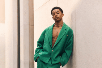 Young model in a green textured suit posing in an urban setting.