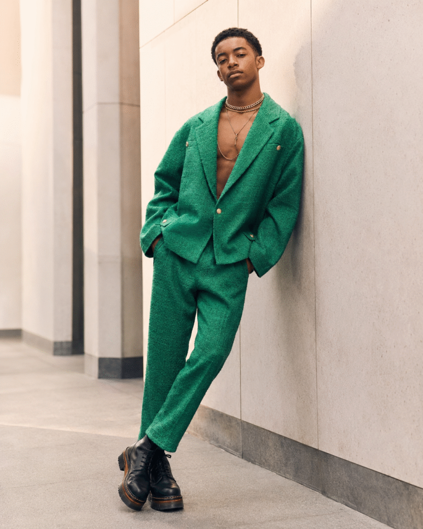 Young model in a green textured suit posing in an urban setting.